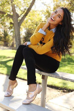 a woman sitting on top of a wooden bench