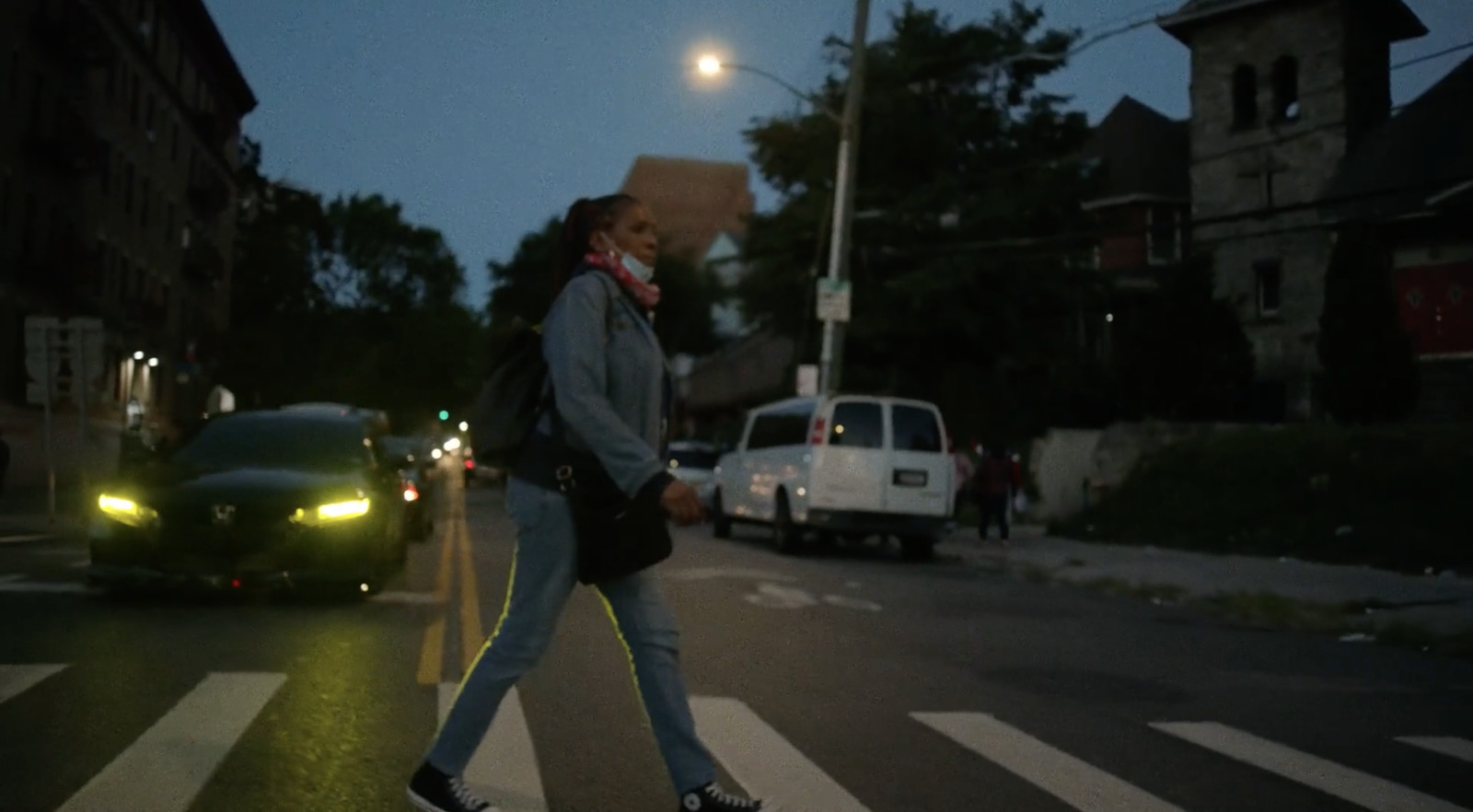 a woman walking across a street at night