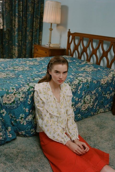 a woman sitting on the floor in front of a bed