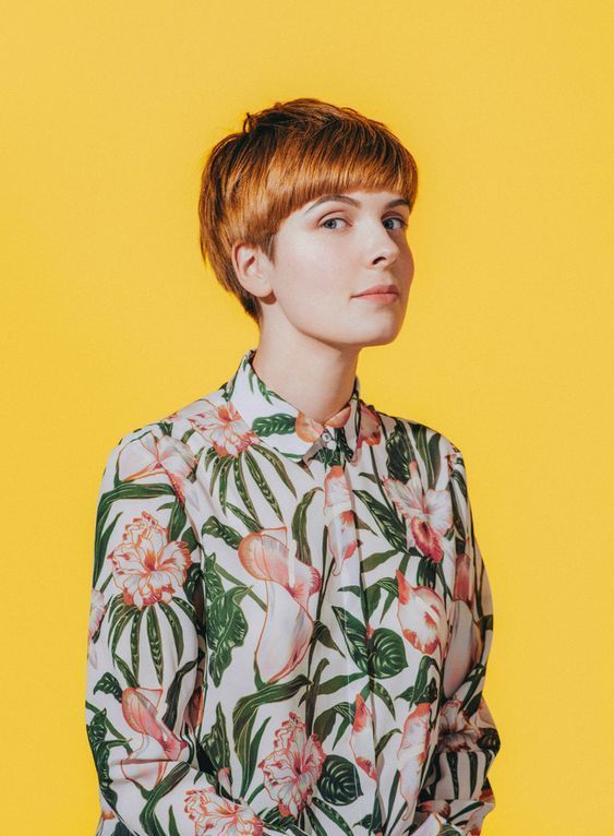 a woman with red hair wearing a floral shirt