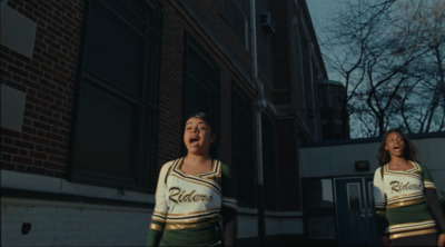 two women in cheerleader outfits standing in front of a building