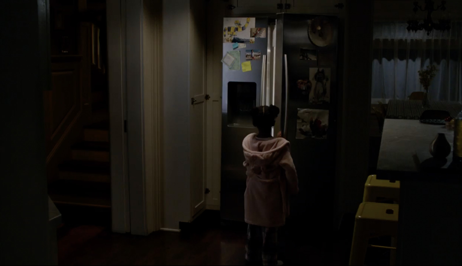 a little girl standing in front of a refrigerator