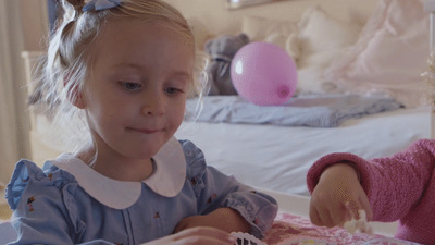 two little girls sitting at a table eating cake