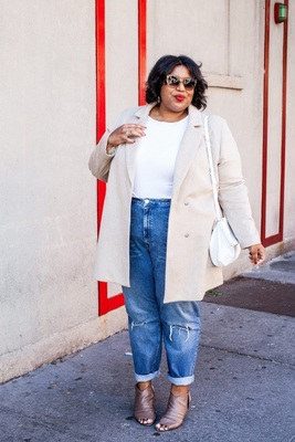 a woman in a white top and jeans standing on a sidewalk