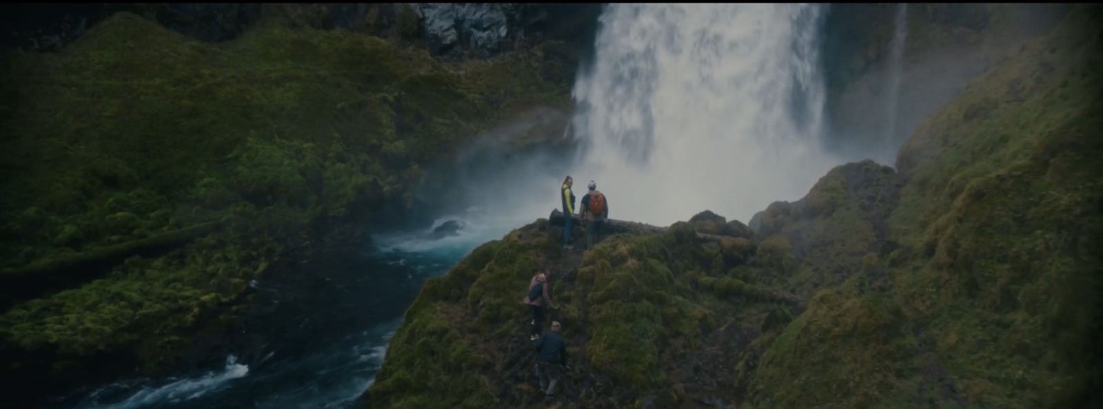 a group of people standing at the base of a waterfall