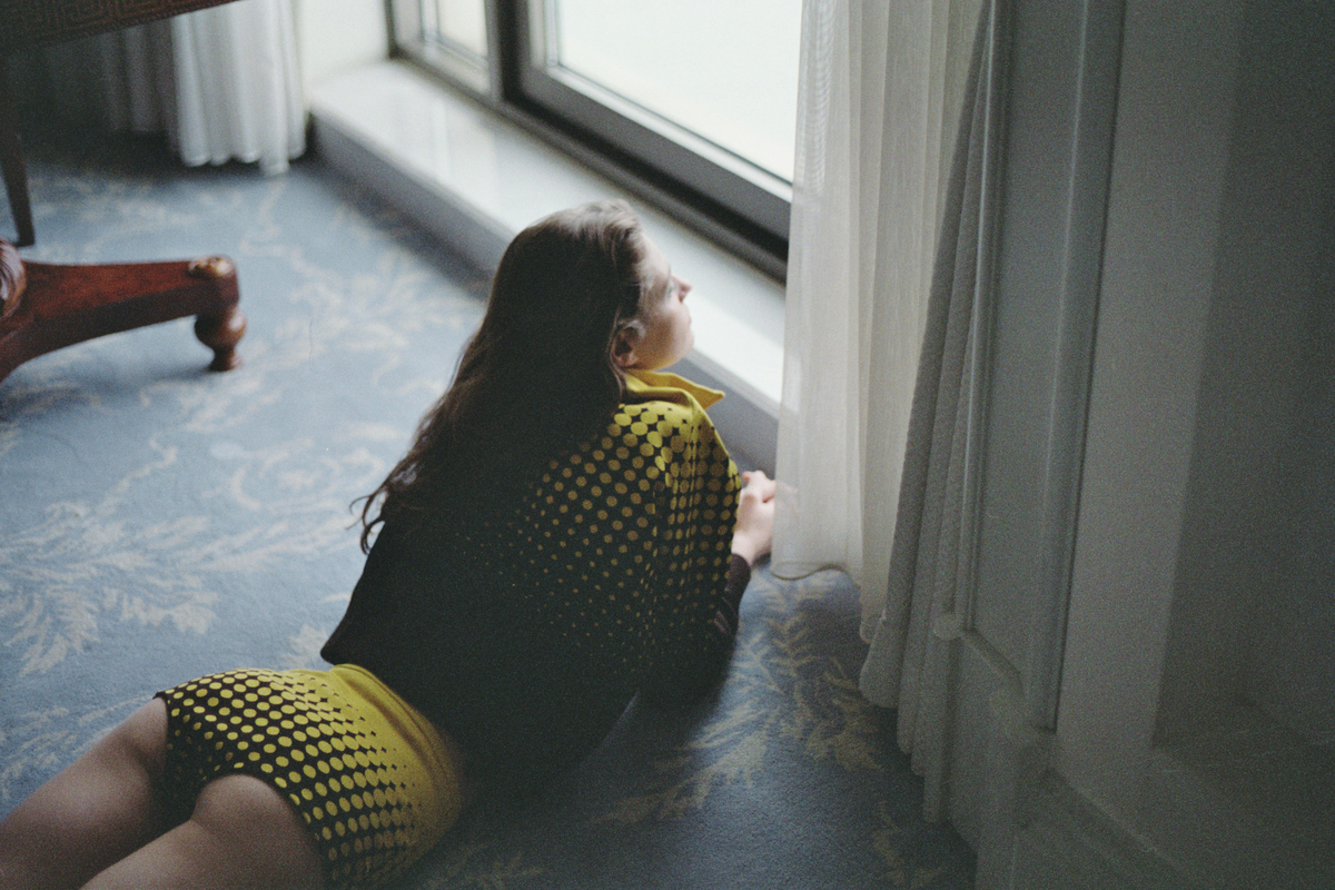 a woman sitting on the floor looking out a window