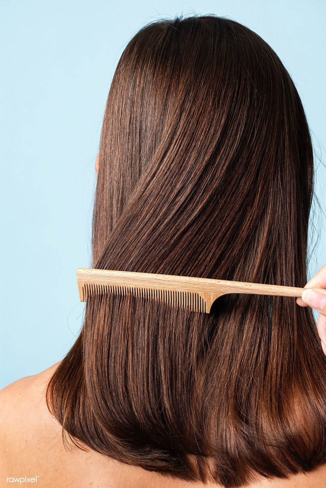 a woman brushing her hair with a wooden comb