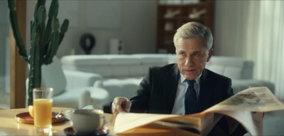 a man sitting at a table reading a newspaper