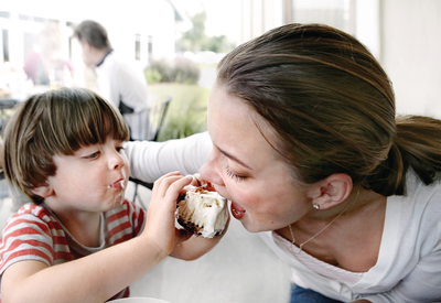 a woman feeding a child a piece of cake