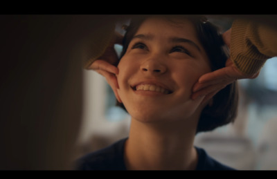 a woman smiling while holding her hands to her ear