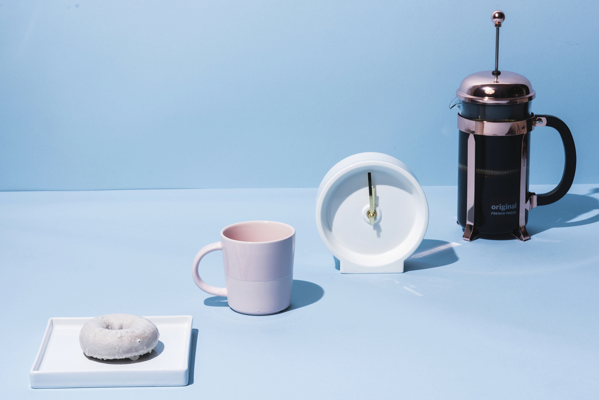 a cup of coffee, a donut, and a coffee maker on a blue