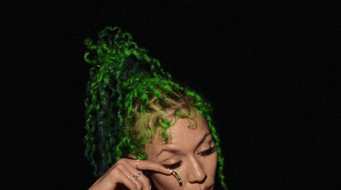 a woman with green dreadlocks talking on a cell phone