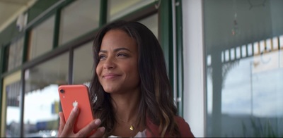 a woman holding a red cell phone in front of a window