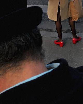 a woman wearing red shoes and a trench coat