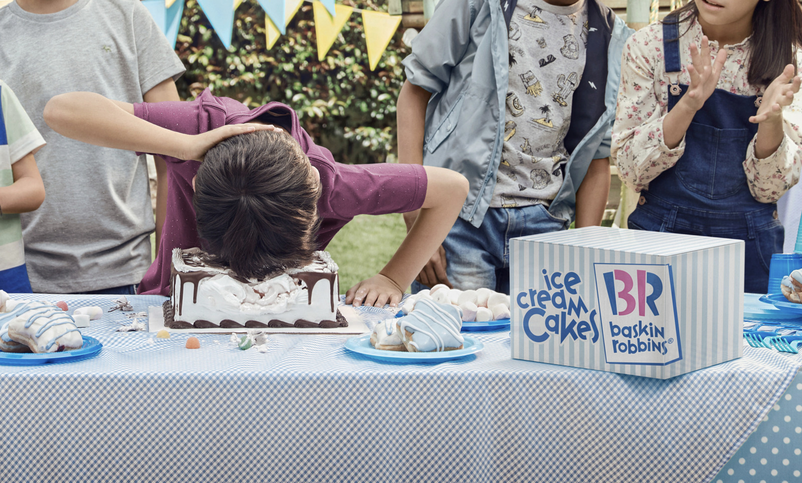 a group of people standing around a table with a cake