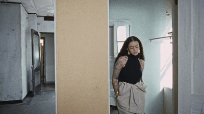 a woman standing in a doorway with a tattoo on her arm