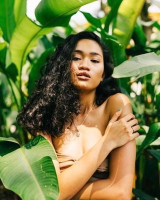 a woman with long hair standing in a jungle