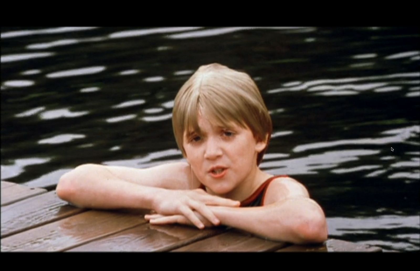 a young boy sitting on a wooden dock