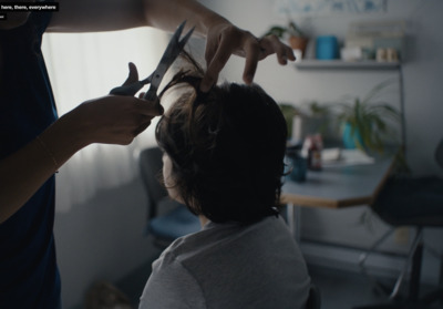 a woman cutting a child's hair with scissors