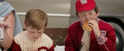 a couple of young boys eating a hot dog