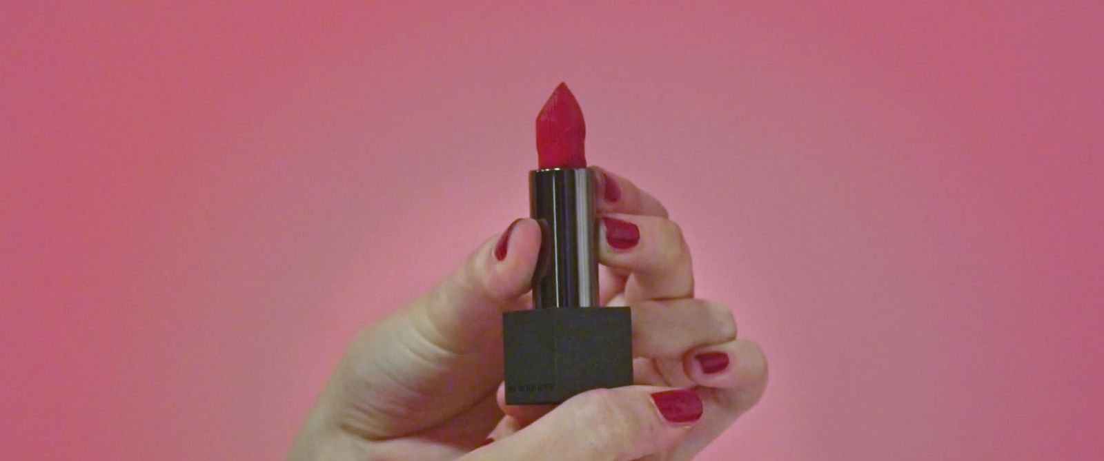 a woman holding a red lipstick in her hand