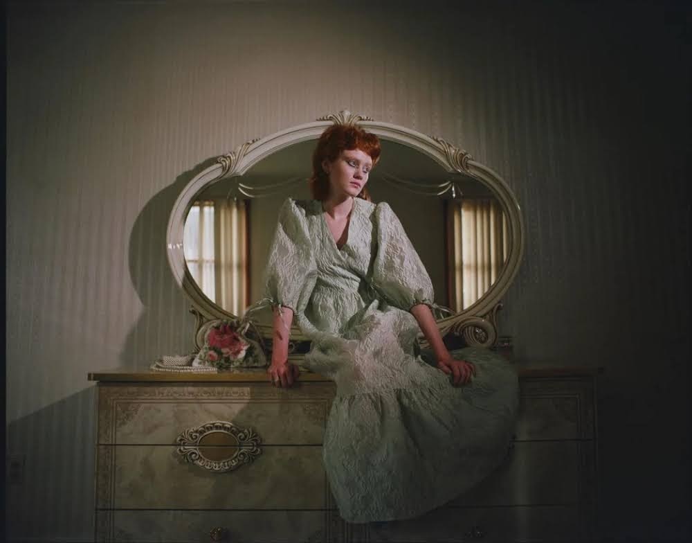 a woman sitting on a dresser in front of a mirror