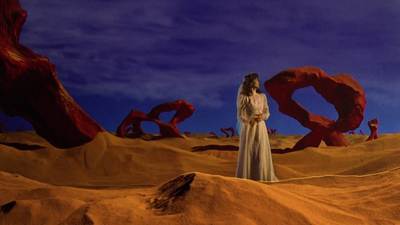 a woman in a white dress standing in a desert