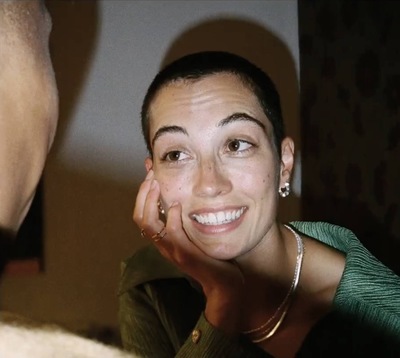 a woman smiles as she holds her hand up to her face