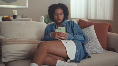 a woman sitting on a couch looking at a cell phone