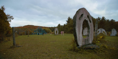 a group of people standing in a field next to a large rock