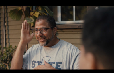 a man in a gray shirt is talking to another man