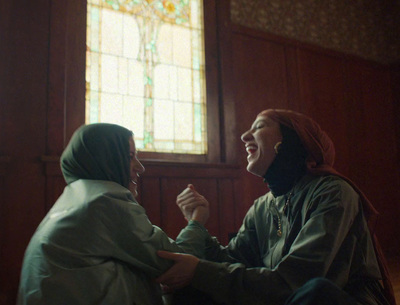 two women sitting next to each other in front of a stained glass window