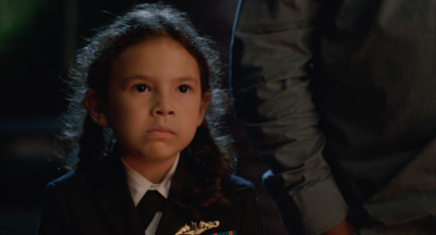 a little girl in a uniform looking at the camera