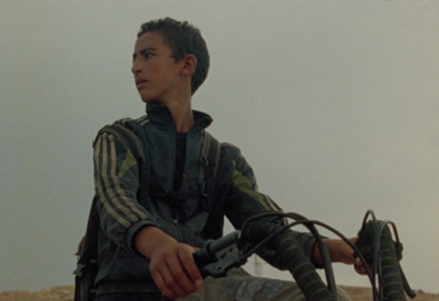 a young man sitting on a motorcycle in the desert