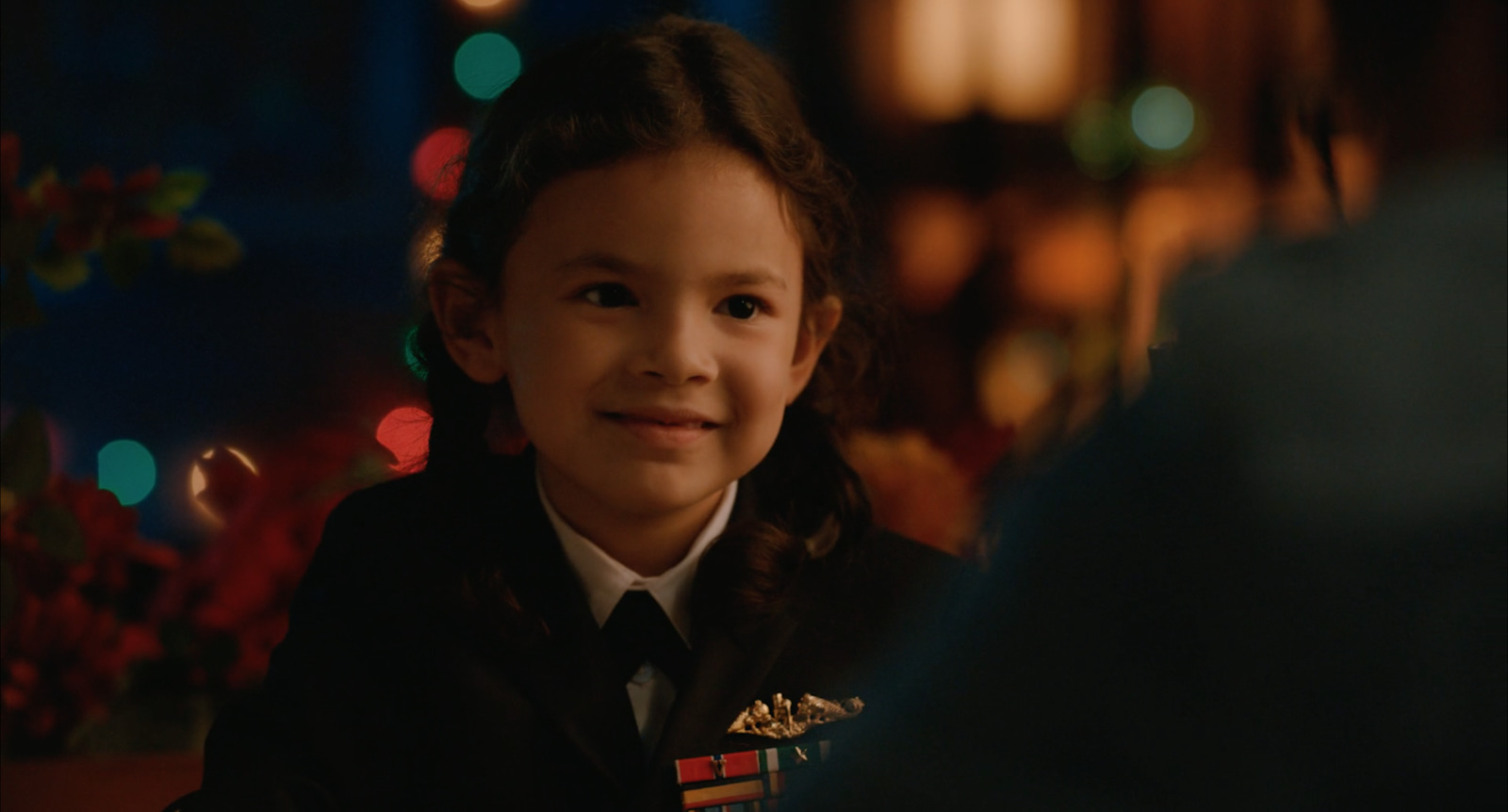 a little girl in a uniform smiling at someone