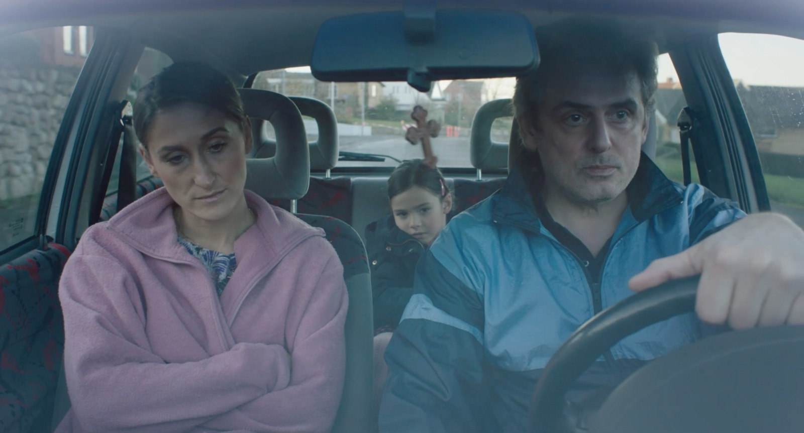 a man driving a car with a woman behind the wheel