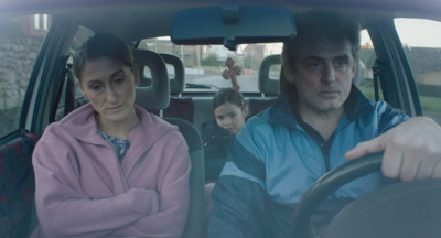 a man driving a car with a woman behind the wheel