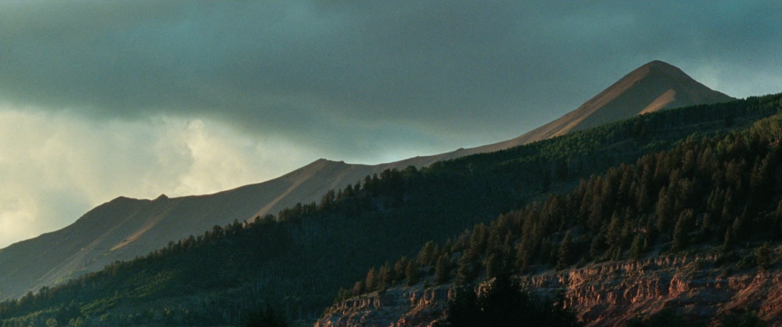 a view of a mountain with trees on the side of it