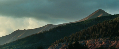 a view of a mountain with trees on the side of it