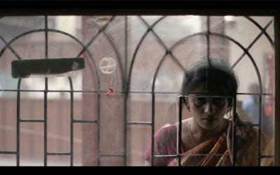 a woman looking out of a window with bars on it