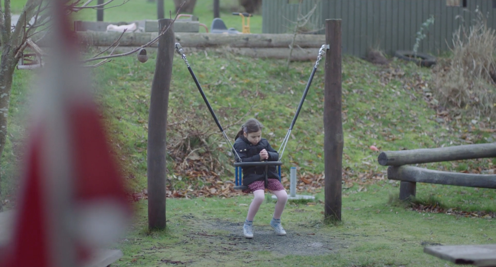 a little girl swinging on a swing in a park