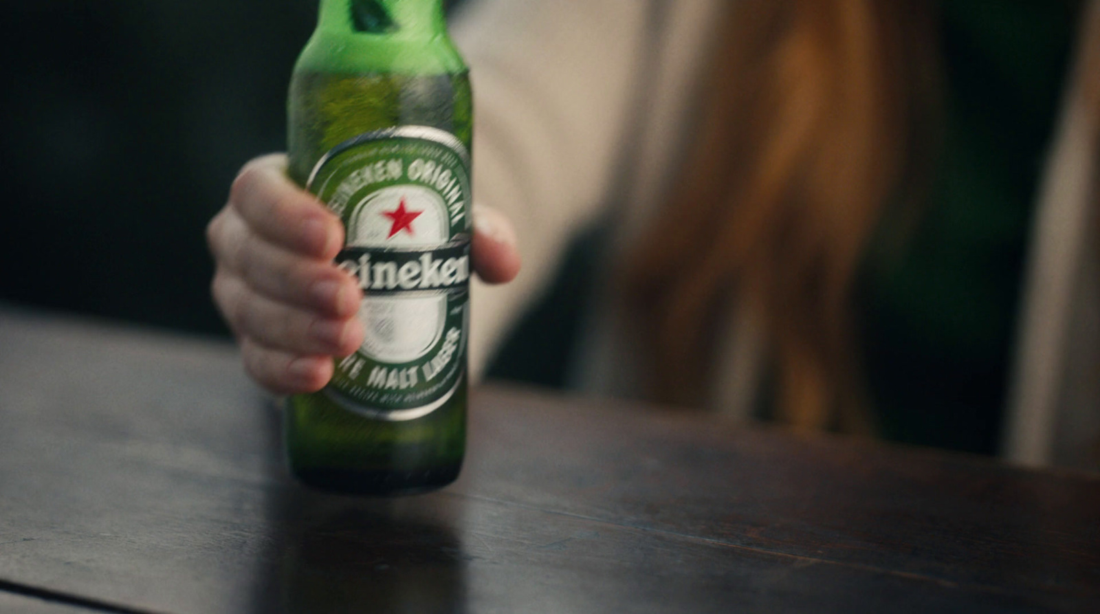 a person holding a beer bottle on a table