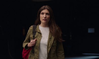 a woman standing in a dark room with a backpack