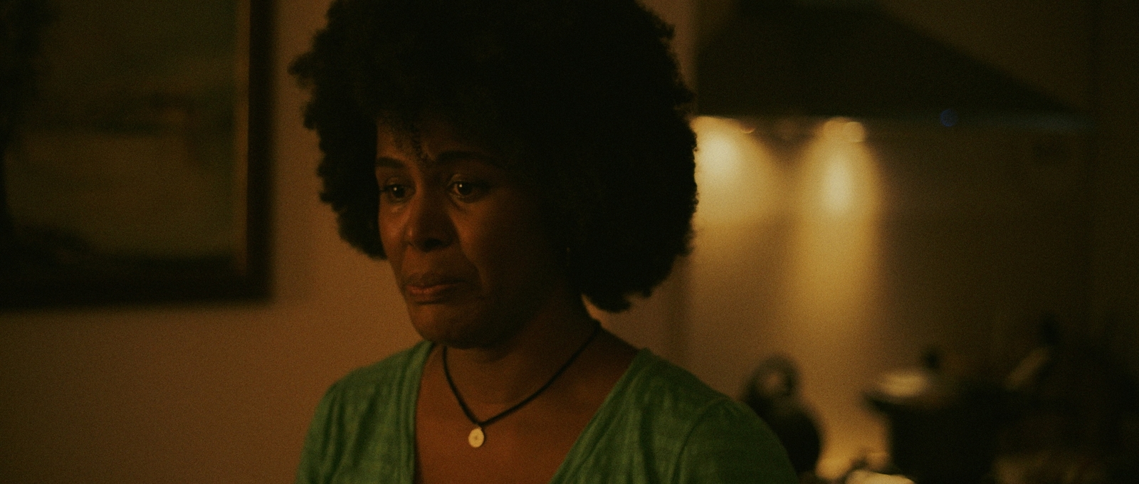 a woman in a green shirt standing in a dark room