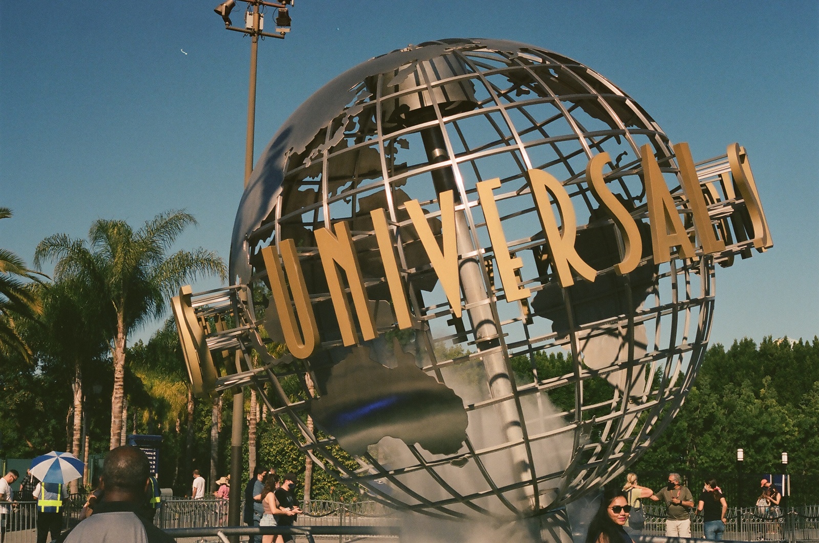 a large metal globe with people walking around it