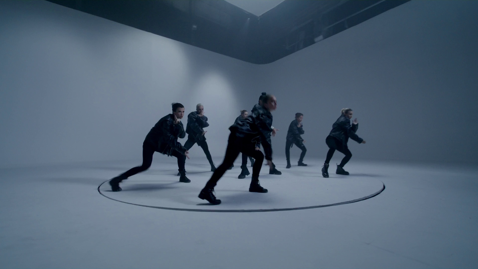 a group of people are dancing in a white room