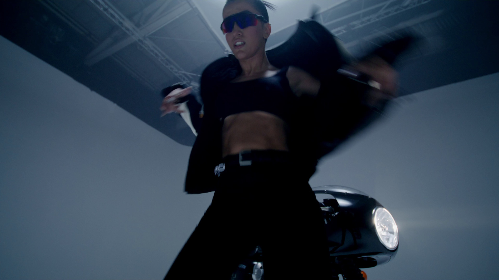 a woman in sunglasses is dancing on a motorcycle