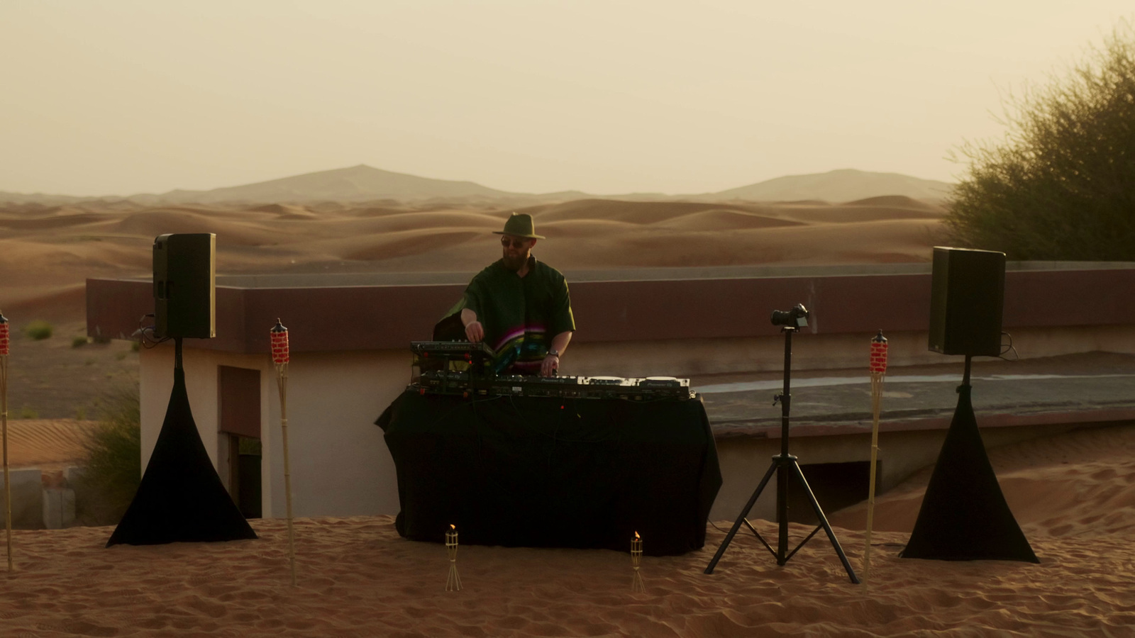 a dj playing music in the desert at sunset