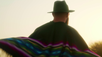 a man wearing a hat and a colorful blanket