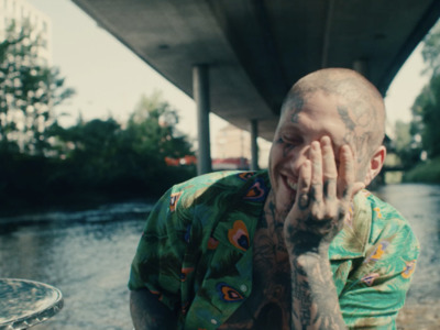 a man with tattoos on his face standing next to a river